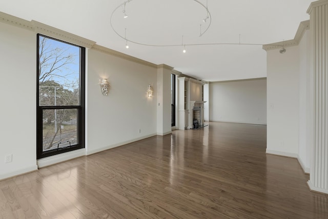 empty room with a healthy amount of sunlight, dark hardwood / wood-style flooring, and crown molding