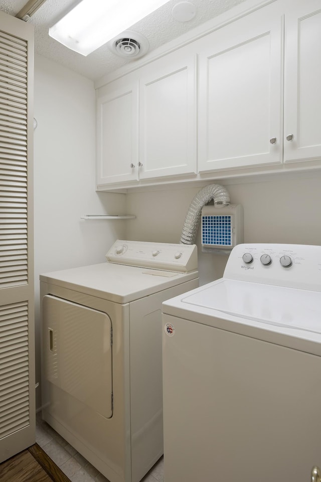 laundry room with cabinets, a textured ceiling, separate washer and dryer, and tile patterned flooring