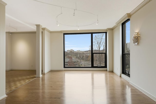 spare room with hardwood / wood-style floors, ornate columns, and crown molding