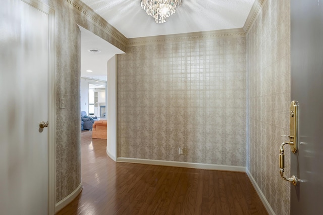 corridor with hardwood / wood-style floors, a notable chandelier, and ornamental molding