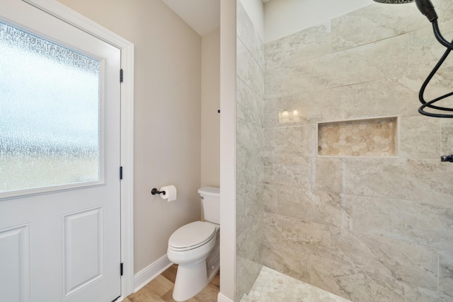 bathroom featuring tiled shower, hardwood / wood-style floors, and toilet