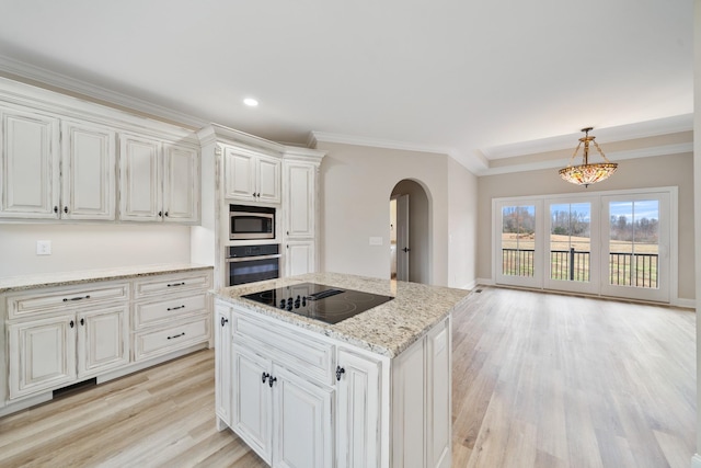 kitchen featuring stainless steel appliances, a kitchen island, decorative light fixtures, light hardwood / wood-style flooring, and white cabinetry