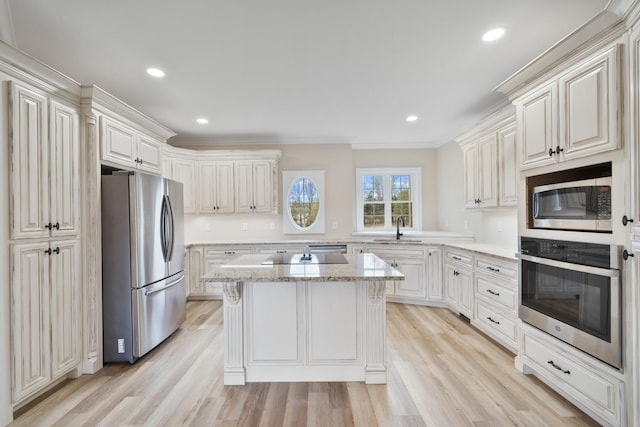 kitchen featuring light wood-type flooring, stainless steel appliances, ornamental molding, and sink