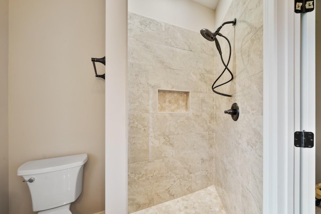 bathroom with a tile shower and toilet