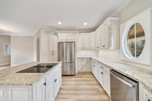 kitchen featuring light stone countertops, appliances with stainless steel finishes, ornamental molding, light hardwood / wood-style flooring, and white cabinets