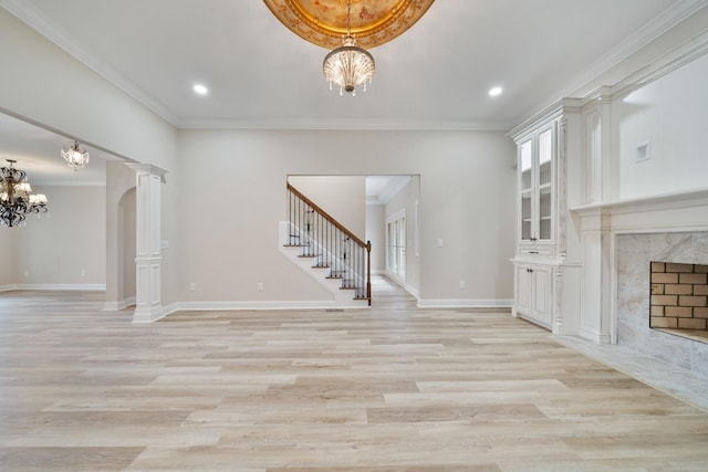 unfurnished living room with a fireplace, light hardwood / wood-style flooring, a notable chandelier, and ornamental molding