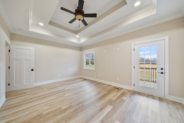 unfurnished room featuring a raised ceiling, crown molding, plenty of natural light, and light hardwood / wood-style flooring