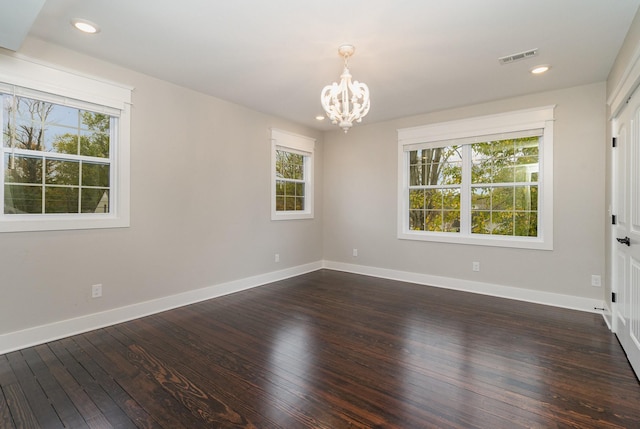 unfurnished room featuring dark hardwood / wood-style flooring and an inviting chandelier