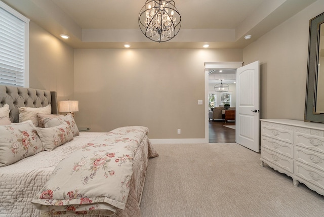 bedroom with a raised ceiling, carpet floors, and an inviting chandelier