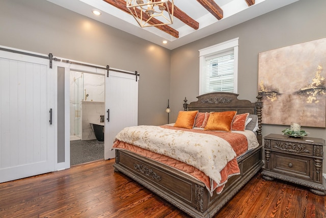 bedroom with beamed ceiling, ensuite bathroom, a barn door, and dark wood-type flooring