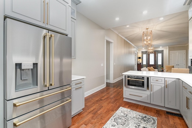 kitchen with stainless steel appliances, gray cabinets, dark wood-type flooring, and a notable chandelier