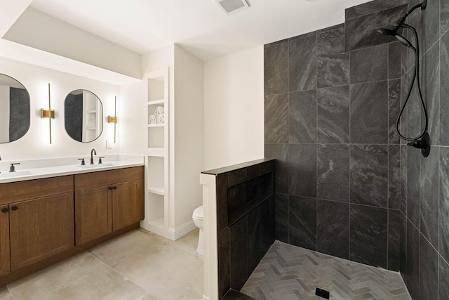 bathroom with vanity, toilet, and tiled shower