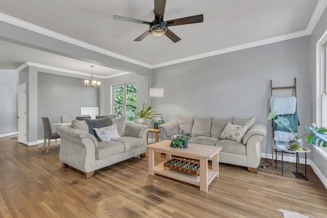 living room featuring hardwood / wood-style floors, ceiling fan with notable chandelier, and ornamental molding