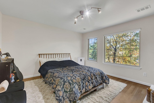 bedroom featuring wood-type flooring and track lighting