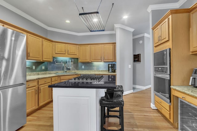 kitchen featuring dark stone counters, stainless steel appliances, sink, a center island, and light hardwood / wood-style floors