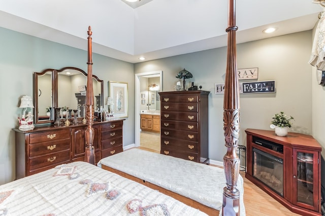 bedroom featuring connected bathroom and light hardwood / wood-style flooring