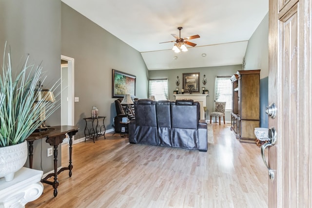 living room featuring ceiling fan, light hardwood / wood-style floors, and lofted ceiling