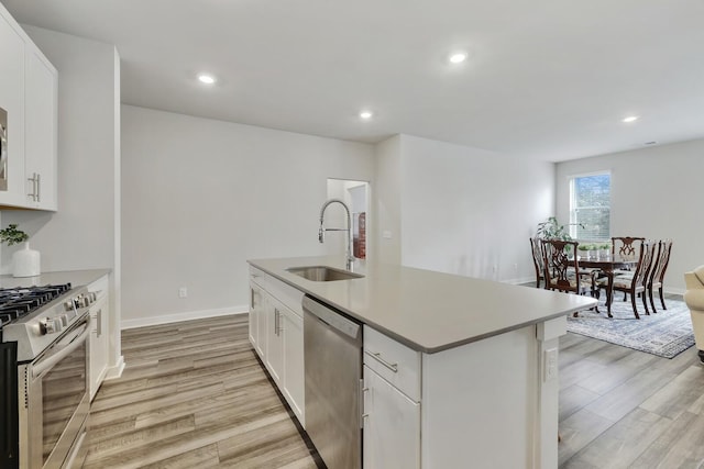 kitchen featuring sink, white cabinets, appliances with stainless steel finishes, and an island with sink