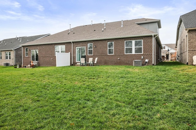 rear view of house featuring central air condition unit and a yard