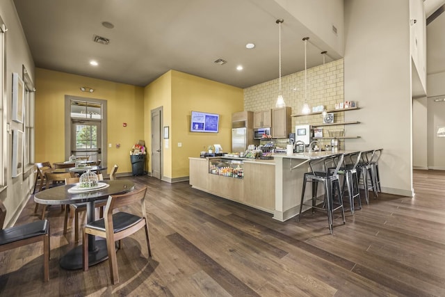 kitchen featuring a kitchen bar, decorative light fixtures, dark hardwood / wood-style flooring, stainless steel appliances, and kitchen peninsula