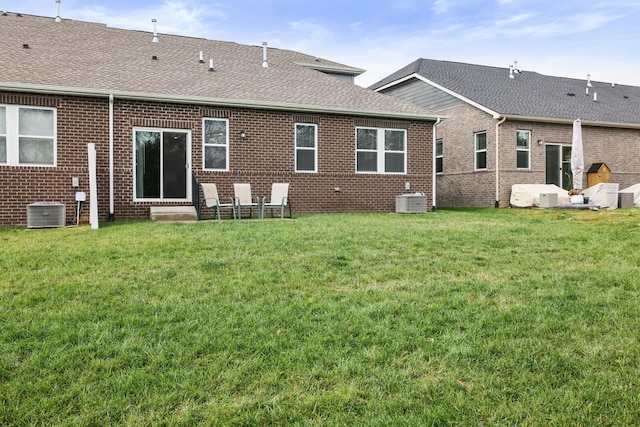 rear view of property with a yard and central AC