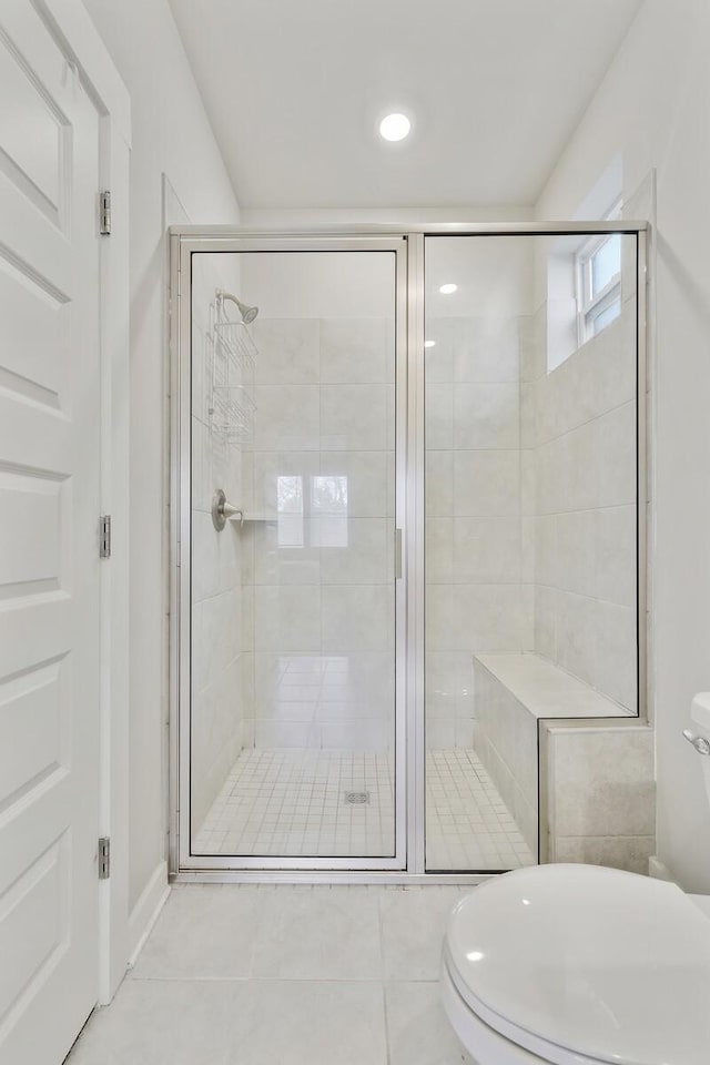 bathroom featuring a shower with shower door, tile patterned floors, and toilet