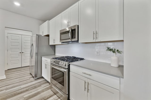 kitchen featuring backsplash, white cabinetry, light hardwood / wood-style flooring, and appliances with stainless steel finishes