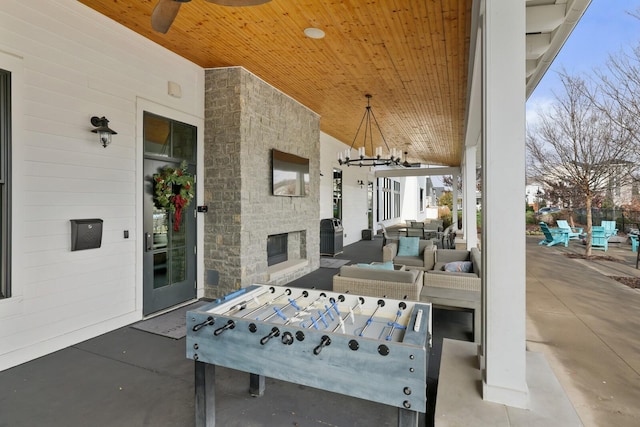 view of patio / terrace with ceiling fan and an outdoor living space with a fireplace