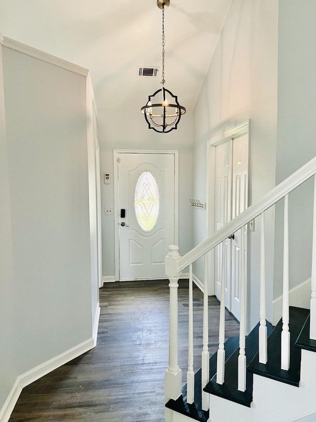 foyer entrance with dark wood-type flooring, high vaulted ceiling, and a chandelier