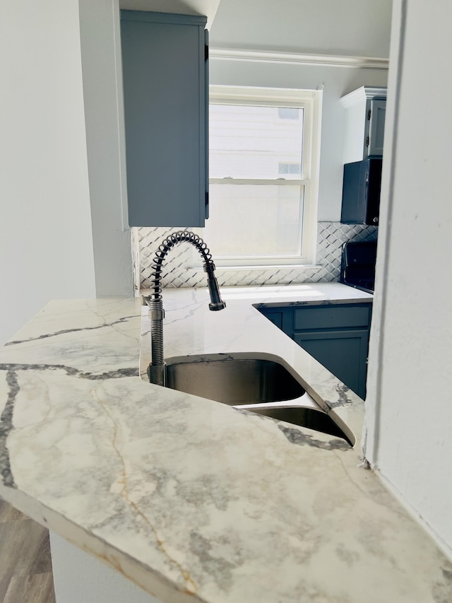 room details with backsplash, blue cabinetry, sink, and hardwood / wood-style floors