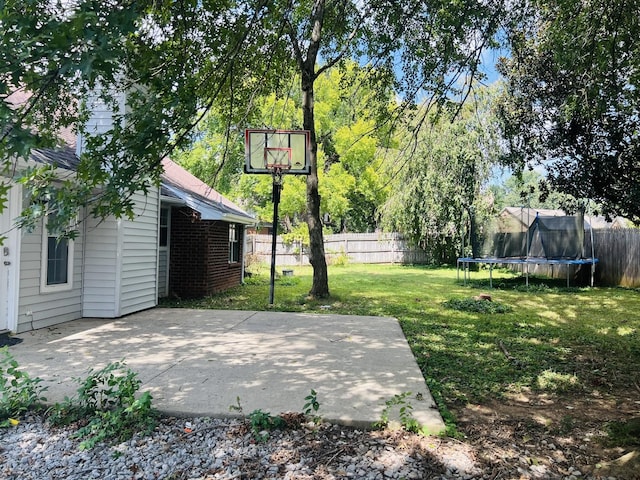 view of basketball court featuring a trampoline and a lawn