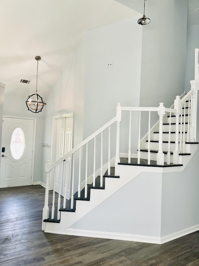 entryway with dark wood-type flooring, high vaulted ceiling, and an inviting chandelier