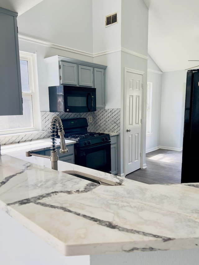 kitchen with backsplash, hardwood / wood-style floors, high vaulted ceiling, and black appliances