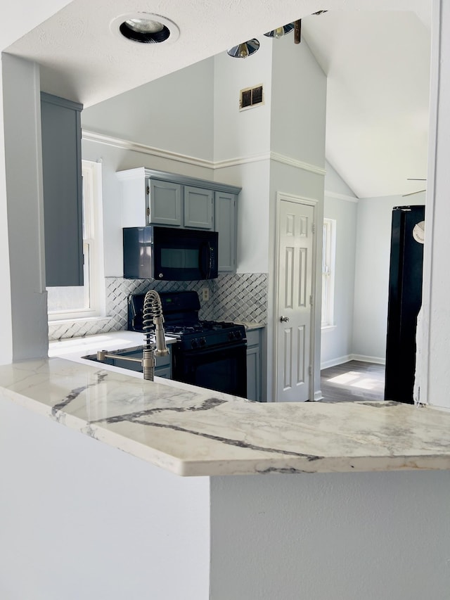 kitchen featuring black appliances, sink, vaulted ceiling, decorative backsplash, and kitchen peninsula