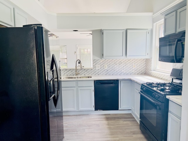 kitchen featuring black appliances, white cabinets, sink, light wood-type flooring, and tasteful backsplash