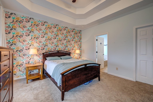 carpeted bedroom with ensuite bathroom, ceiling fan, ornamental molding, and a tray ceiling