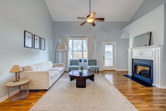 living room with hardwood / wood-style flooring, ceiling fan, and high vaulted ceiling