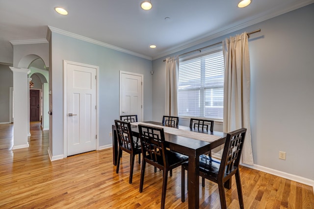 dining area with ornate columns, ornamental molding, and light wood-type flooring