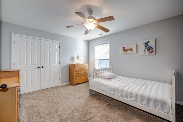 bedroom with ceiling fan, light carpet, and a closet