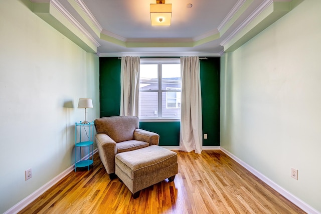 living area with a raised ceiling, crown molding, and light hardwood / wood-style flooring