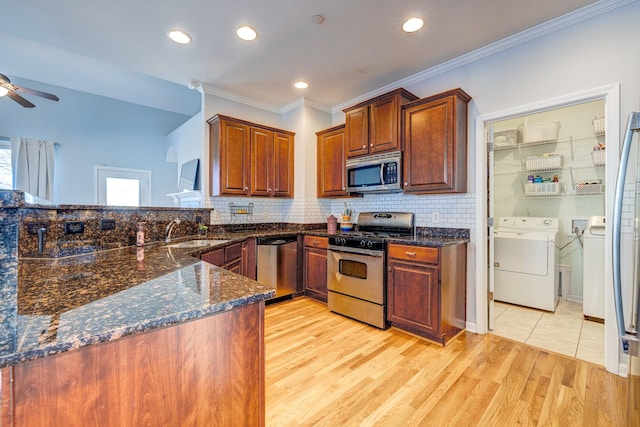 kitchen with appliances with stainless steel finishes, crown molding, sink, light hardwood / wood-style flooring, and washing machine and dryer