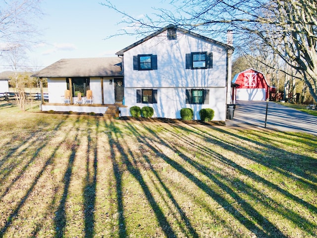 view of front of home featuring a garage, a front lawn, and an outdoor structure