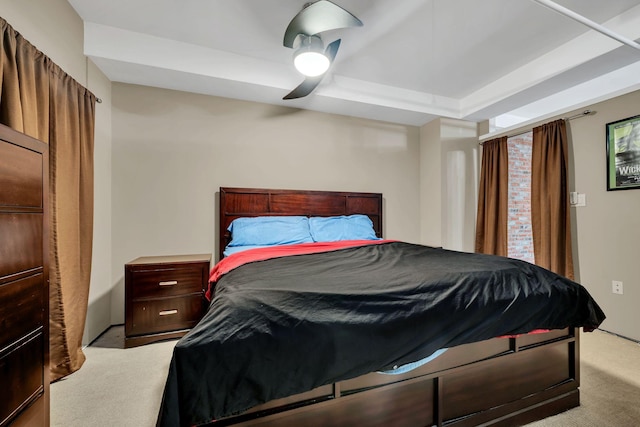 bedroom with ceiling fan, light carpet, and a tray ceiling