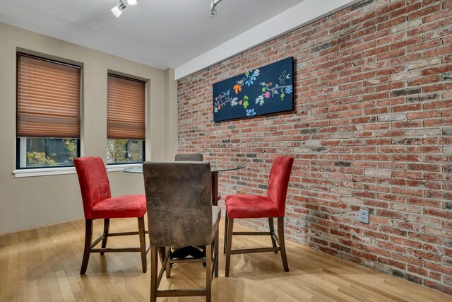 dining space featuring light hardwood / wood-style floors and brick wall