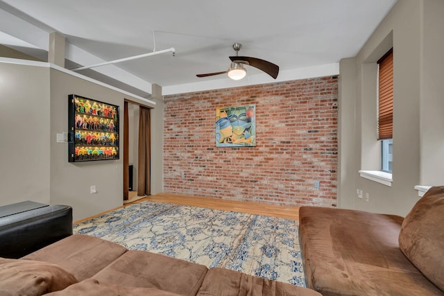 living room with hardwood / wood-style flooring, ceiling fan, and brick wall