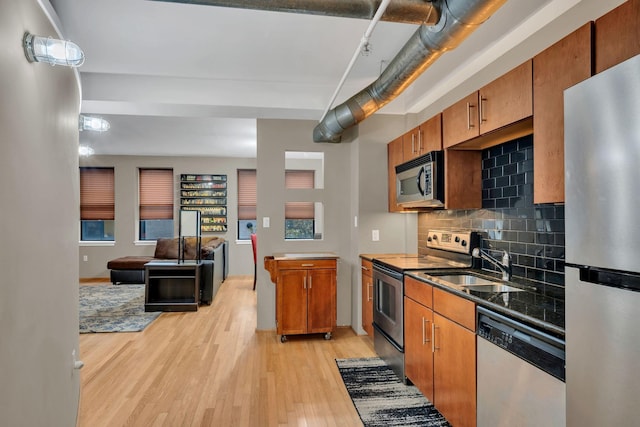 kitchen with light hardwood / wood-style floors, sink, appliances with stainless steel finishes, and tasteful backsplash