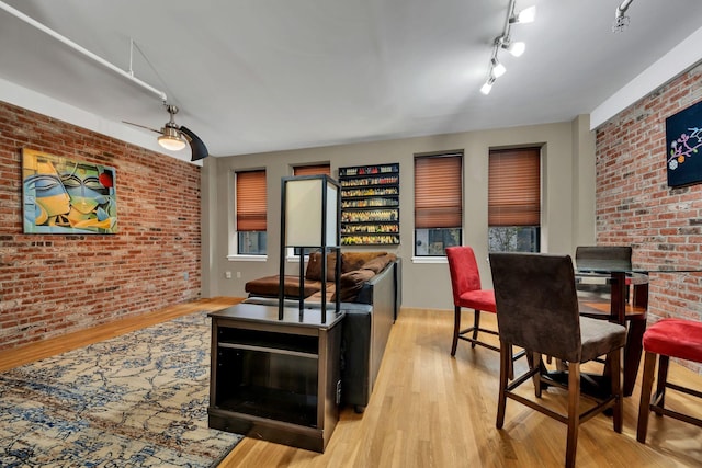 living room featuring light hardwood / wood-style floors, ceiling fan, and brick wall