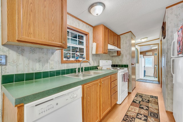 kitchen with a textured ceiling, light wood-type flooring, white appliances, and sink