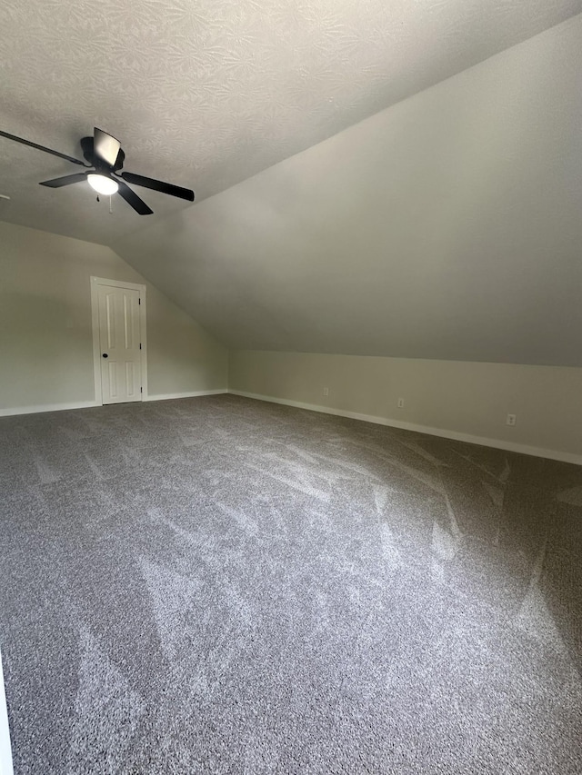 bonus room featuring a textured ceiling, ceiling fan, carpet, and vaulted ceiling