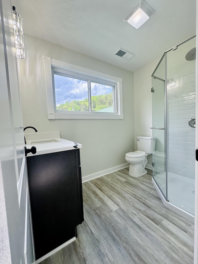 bathroom with wood-type flooring, vanity, a textured ceiling, and a shower with door